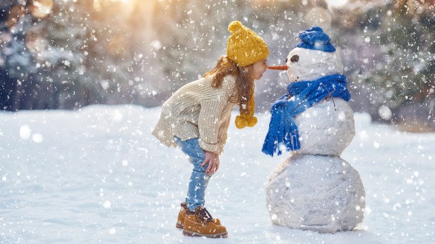 Ein Mädchen steht vor einem Schneemann