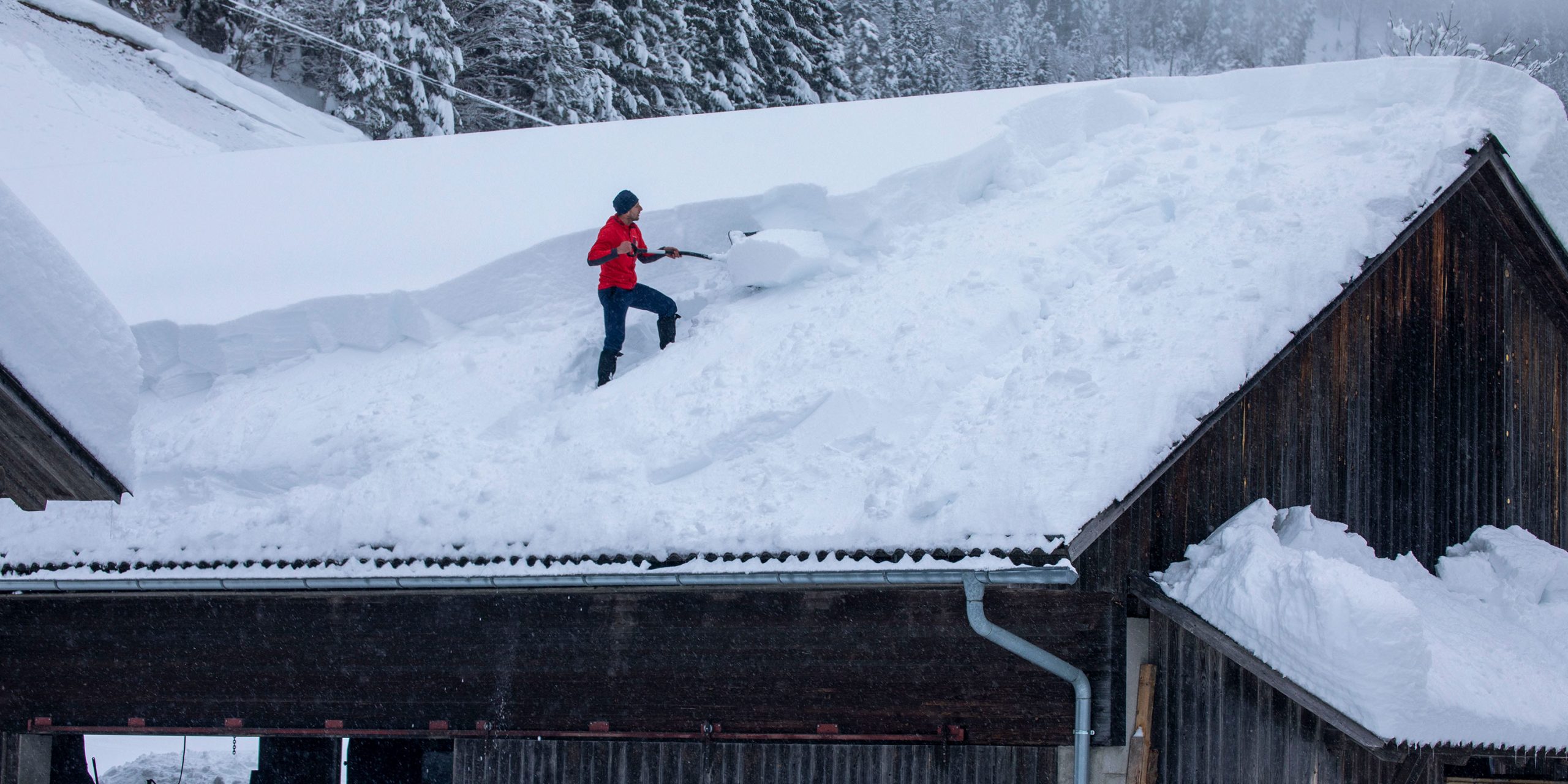 Mann räumt Schnee von Dach